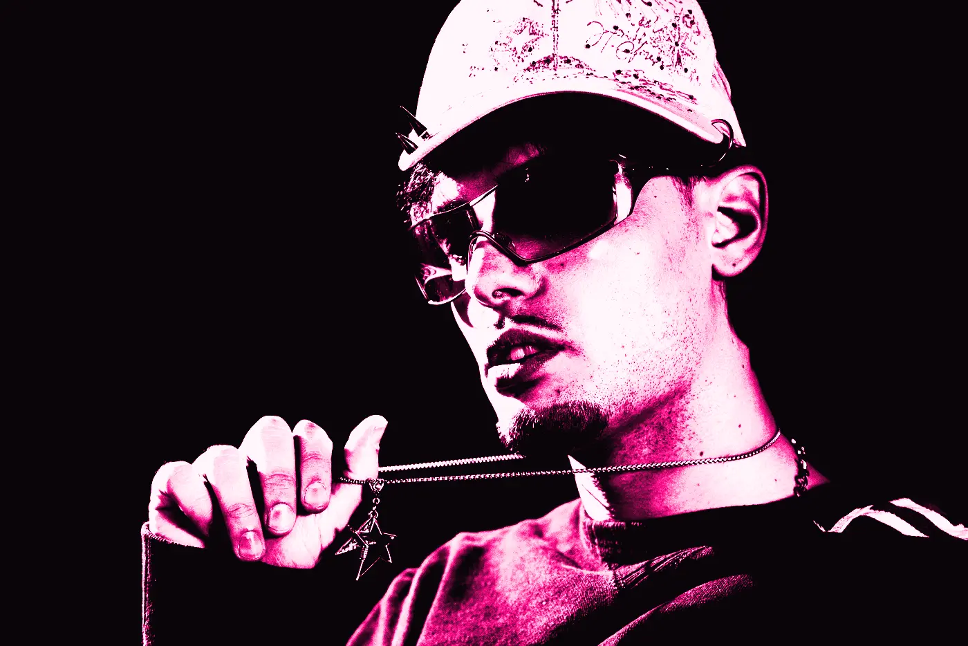 Retrato de 7TY con gafas de sol y gorra, sujetando el colgante de estrella